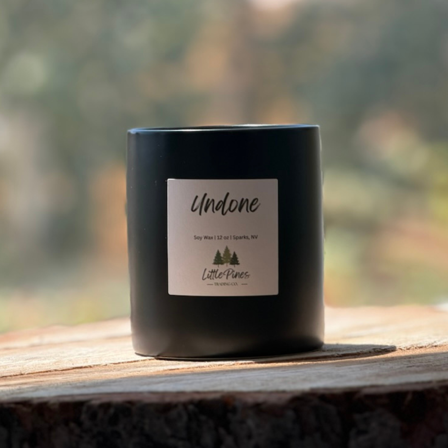 Black candle with a label on a wooden surface with a blurred natural background